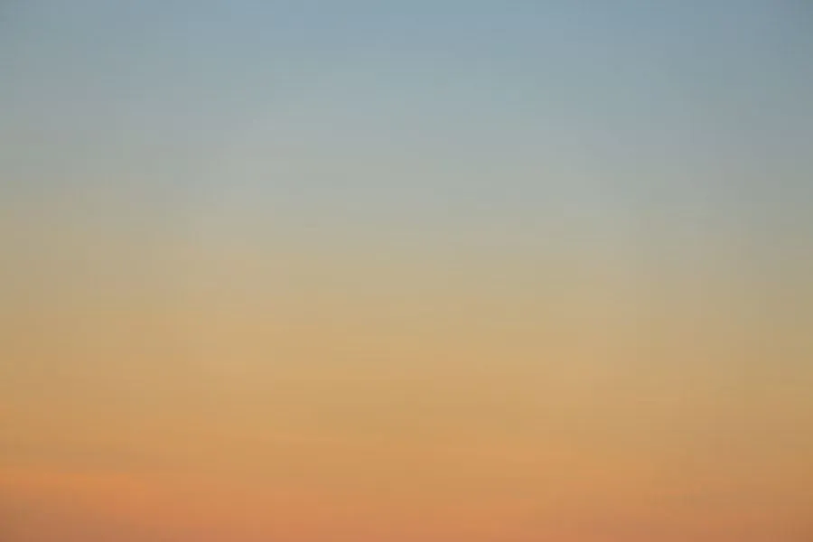 A soft dawn sky shading from pale blue into warm amber light