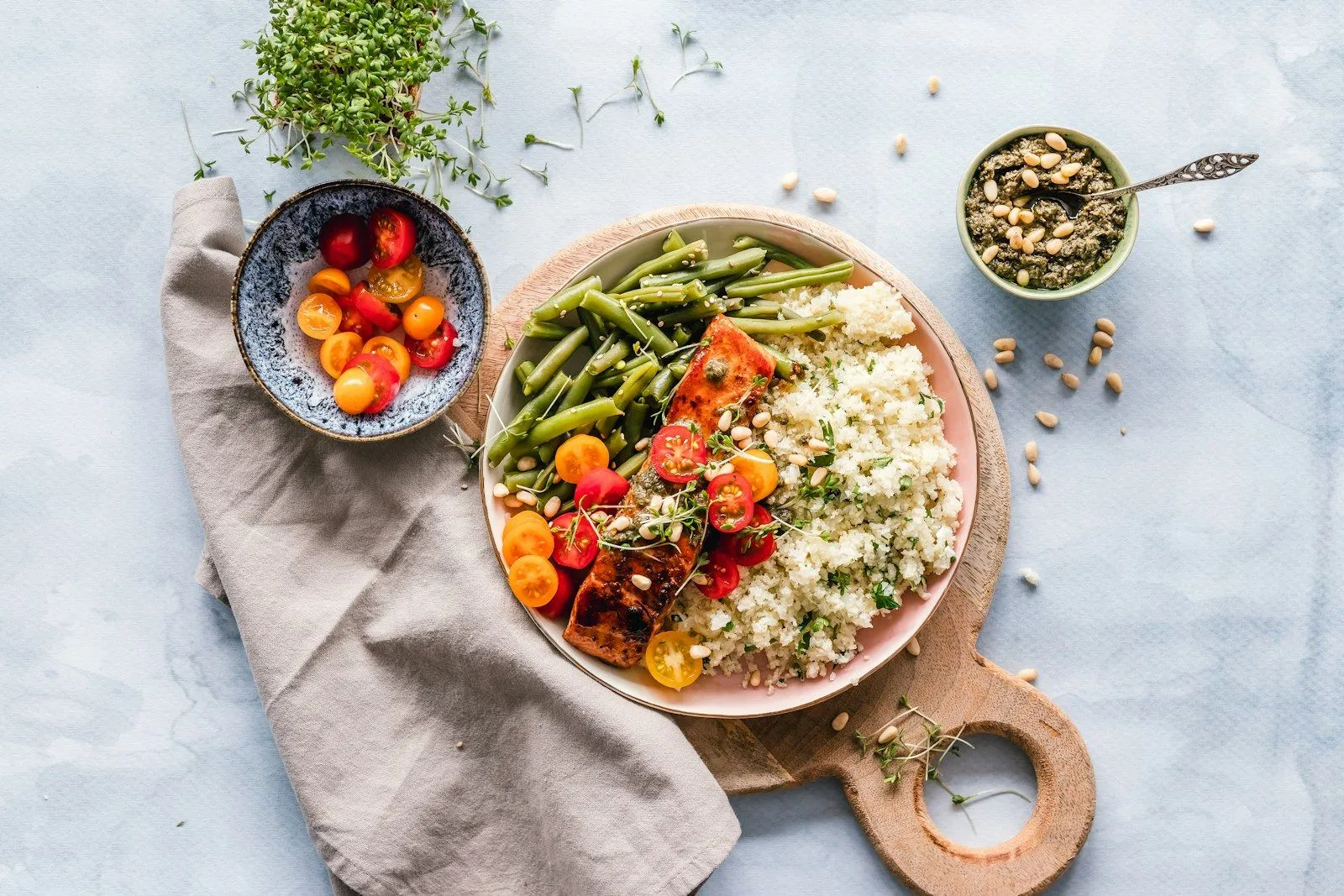 A shared table: a grain bowl with vegetables, seeds and herbs in natural light